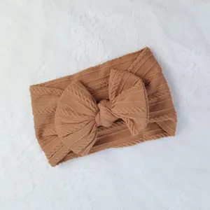 Diadema suave para bebé en punto de ochos marrón con un gran lazo de nailon.