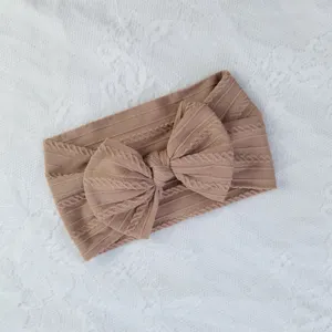 Primer plano de una diadema para bebé de nailon marrón con punto trenzado y lazo