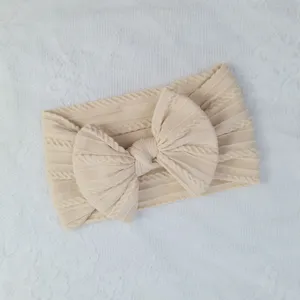 Primer plano de una diadema de punto de ochos para bebé en color crema con un lazo