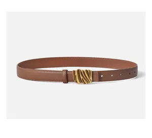 Close-up of women's brown leather belt with stylish wavy gold metal buckle detail.