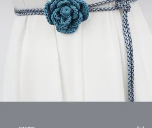 Close-up detail of a handmade braided waist chain with a chic blue flower on a white dress.