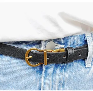 Schmaler schwarzer Ledergürtel mit antiker goldener Dornschnalle an blauen Jeans.