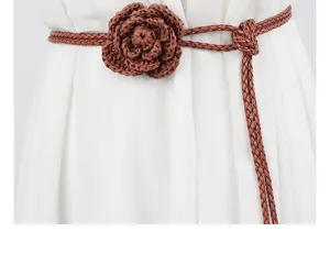 Close-up detail of a brown braided waist belt featuring a handmade crochet flower design.