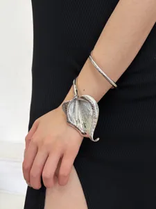 Close-up detail of vintage exaggerated 3D leaf metal cuff bracelet and smooth bangle.