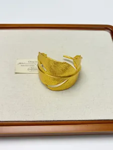 Golden leaf cuff bracelet detail, unique metal design open bangle accessory for women.