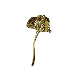 Close-up detail of the vintage gold pleated leaf brooch, showing metallic texture and shape.
