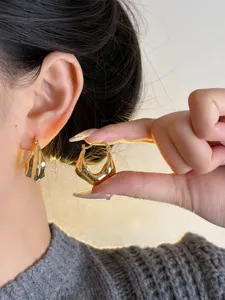 Close-up view of unique geometric metal earrings, showing shiny gold finish and modern design.