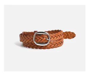 Dettaglio della cintura intrecciata in pelle marrone con elegante fibbia ovale argentata.