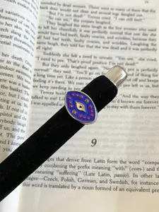 Close-up of a blue enamel evil eye celestial metal open ring displayed on a book page.