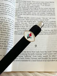 Detailed close-up of vintage black velvet enamel ring with red floral design on open book.