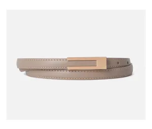 Close-up detail of a minimalist women's thin leather belt with a sleek gold rectangular buckle.