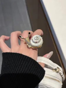 Nahaufnahme des kreativen Schneckenhaus-Rings mit glitzernden Strasssteinen und goldenem Finish.