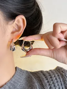 Detailed close-up view of irregular metallic geometric hoop earrings worn on ear and hand display