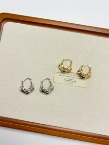 Close-up detail shot of irregular geometric metal earrings in gold and silver on a tray display.