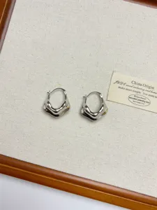Close-up detail of silver geometric metal earrings, showcasing retro abstract design.