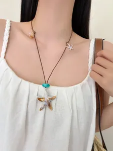 Close-up detail of bohemian ocean style starfish and shell necklace pendant accessory.