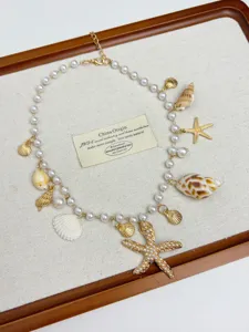 Detail view of a bohemian ocean style starfish pendant necklace with pearls and shells.