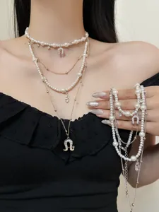 Detailed view of multi-layered pearl and metal necklace with horseshoe pendant.
