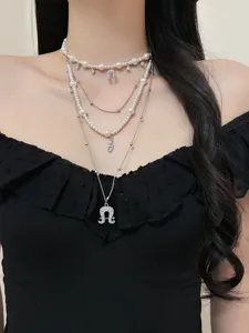 Close-up view of multi-layer pearl and silver chain necklace with horseshoe pendant details.