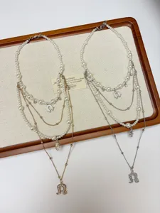 Close-up detail of multi-layer pearl necklaces with horseshoe pendants on display tray.