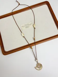 Detail view of boho shell pendant necklace with adjustable brown cord and beaded accents.