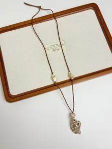 Bohemian shell pendant necklace detail shot showcasing the natural wooden tray display.