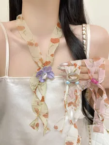 Close-up detail shot of vintage floral silk scarf necklace with beaded elements, chic spring jewelry.