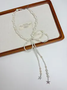 Detailed closeup of the elegant pearl bow necklace with star pendants, vintage style jewelry piece.