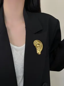 Vue détaillée de la broche oreille dorée, design surréaliste unique pour accessoires de mode.