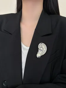 Gros plan sur la broche oreille en métal argenté unique, design artistique élégant.