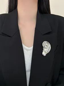 Gros plan sur l'unique broche d'oreille en métal au design surréaliste et élégant.