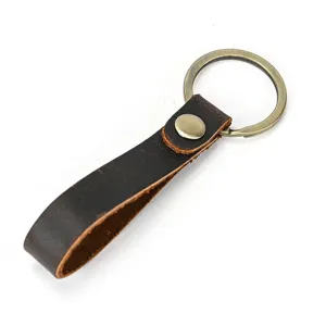 Gedetailleerd overzicht van vintage leren sleutelhanger met stevige metalen ring en drukknoop.