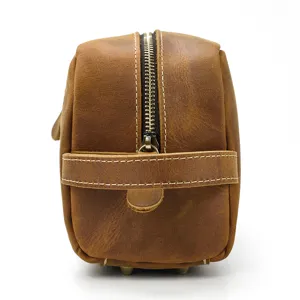 Detail view of brown genuine leather toiletry bag featuring durable metal zipper and side handle.