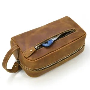 Detail view of brown genuine leather toiletry bag zipper pocket and side handle design.