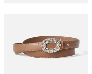 Close-up detail of brown leather belt with sparkling crystal rhinestone oval buckle.