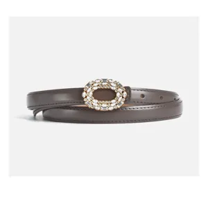 Close-up detail of the brown leather belt with shiny crystal rhinestone oval buckle.