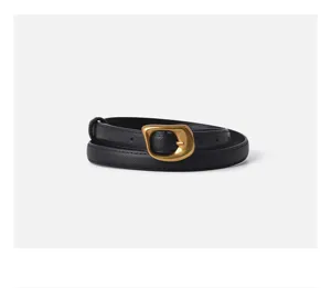 Close-up view of the black leather belt featuring a unique sculptural gold buckle and fine edge stitching.