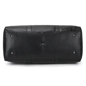 Vue détaillée du fond du sac de voyage en cuir noir avec clous de protection métalliques.