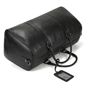 Vue détaillée de la texture du sac de voyage en cuir grainé noir et ferrures métalliques.