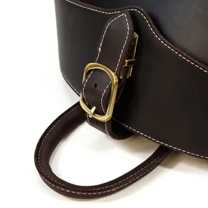 Close-up detail of genuine leather backpack showcasing buckle strap, contrast stitching and handle.