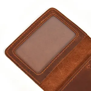 Handmade leather card holder detail view with transparent ID window and fine stitching.