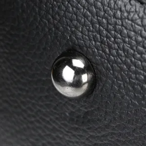 Gros plan détaillé du clou de fond en métal et du cuir texturé du sac de voyage.