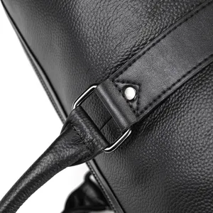 Gros plan détaillé d'un sac de voyage en cuir noir avec des ferrures métalliques.