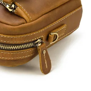 Gros plan sur la fermeture éclair du sac en cuir marron avec des coutures et anneau métal.