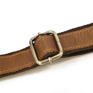 Close-up detail shot of vintage leather bag strap adjuster buckle with metal hardware.
