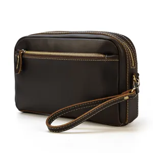 Vue détaillée du sac à poignet en cuir marron foncé avec fermetures éclair et coutures.
