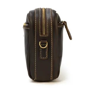 Vue rapprochée du côté d'un sac bandoulière pour homme en cuir marron foncé avec fermeture éclair.