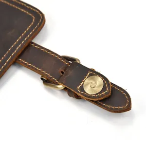 Detailed shot of genuine crazy horse leather backpack strap with vintage brass metal buckle hardware.