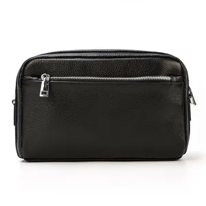 Détail de la pochette en cuir noir véritable avec texture fine et fermeture argentée.