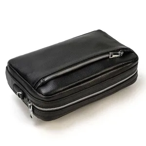 Vue détail de pochette homme en cuir noir, design multi-fermetures éclair et belle texture.